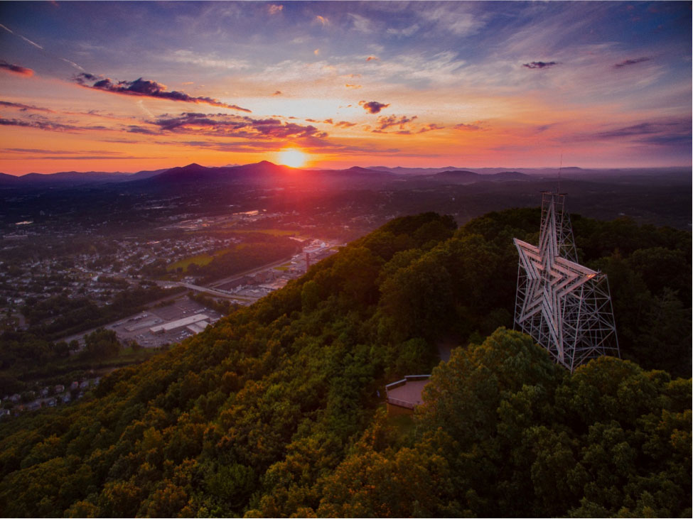 The sun sets behind the mountains near the Roanoke Star.