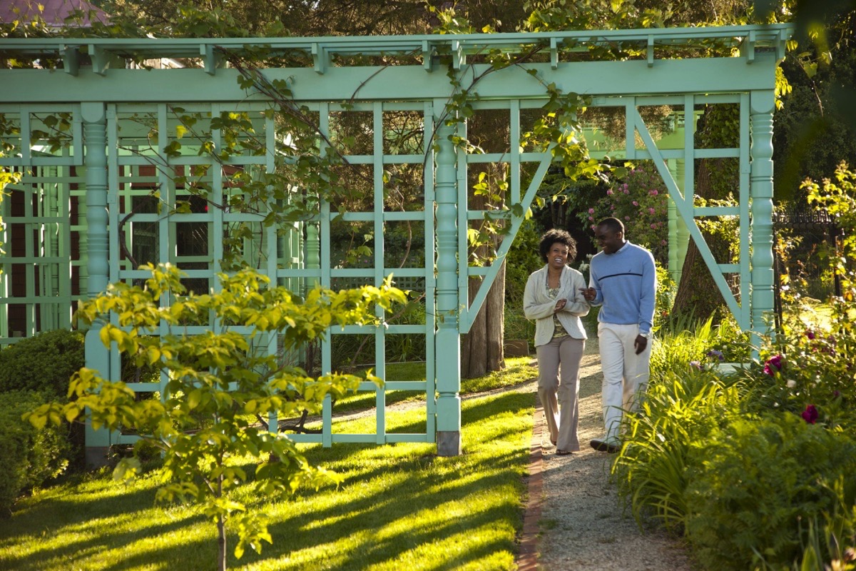 A couple strolls through a manicured garden.