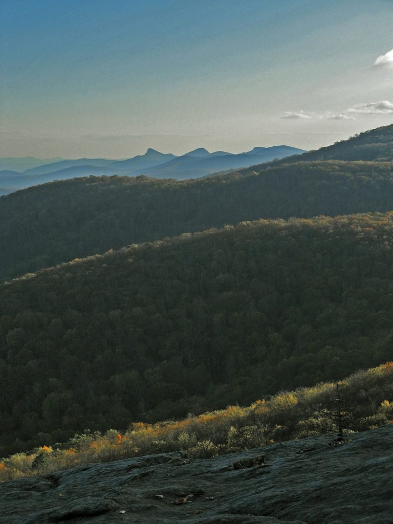 A hike in Linville Gorge offers views of rows of forested mountains, rugged rocky terrain, and multiple waterfalls.