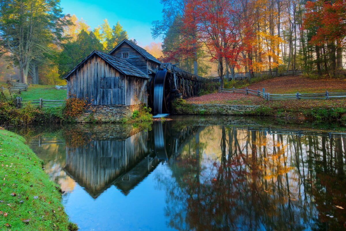 Water spills over the wheel at Mabry Mill surrounded by Fall color.