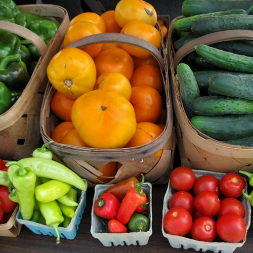 Various sizes and colors of tomatoes, peppers and cucumbers fresh from the farm await purchase at a farm stand.