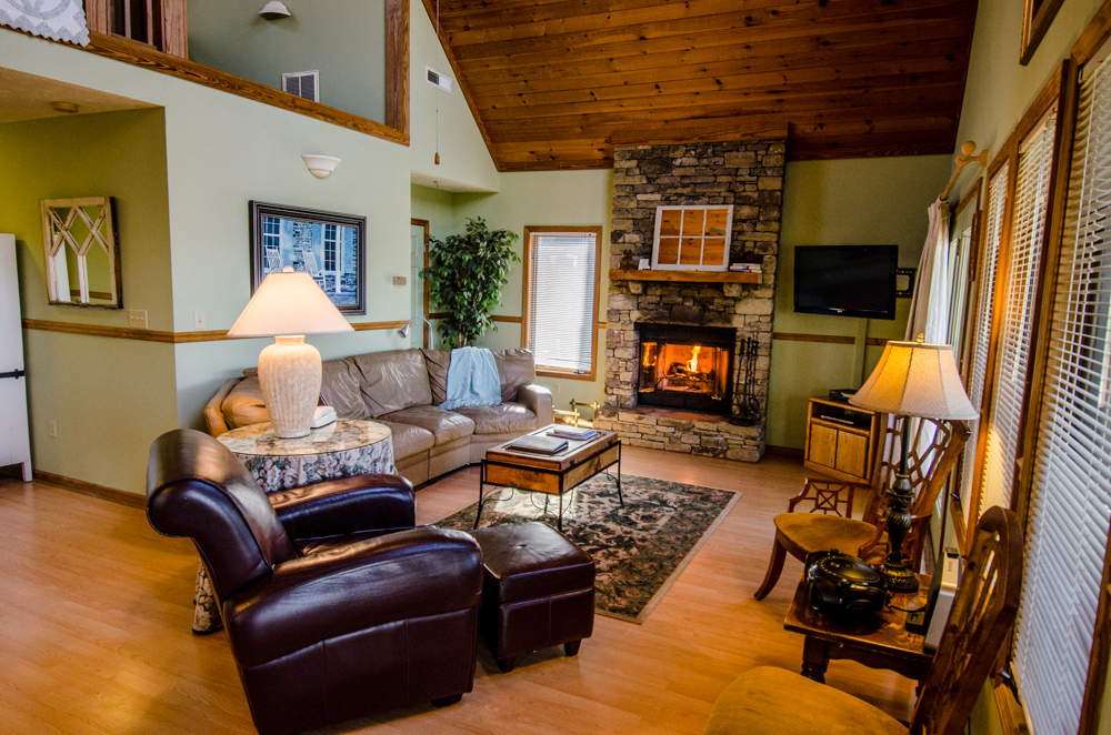Fire glows in the stone fireplace of a cozy rentable home by Asheville Cabins of willow Winds.