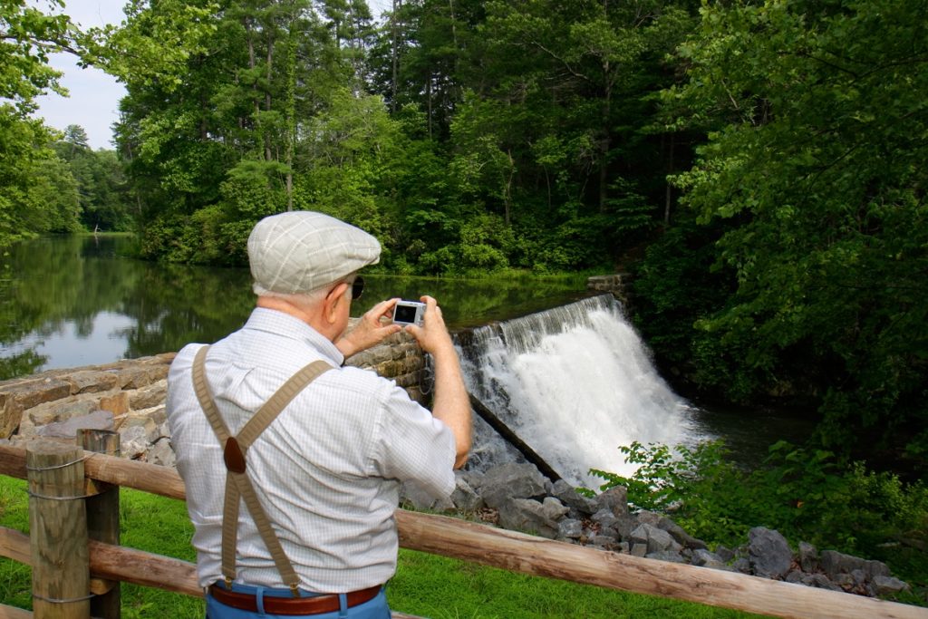 a man takes a photo of a waterfall created by a canal