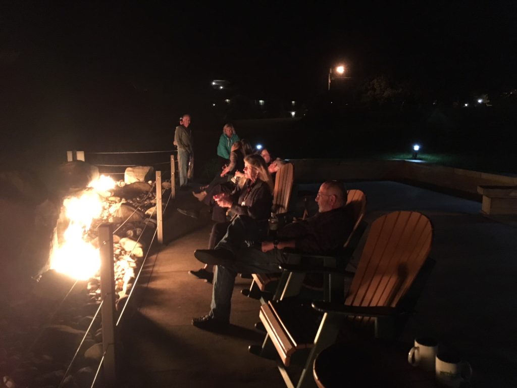 Meeting attendees gather around the outdoor fire pit after dark.