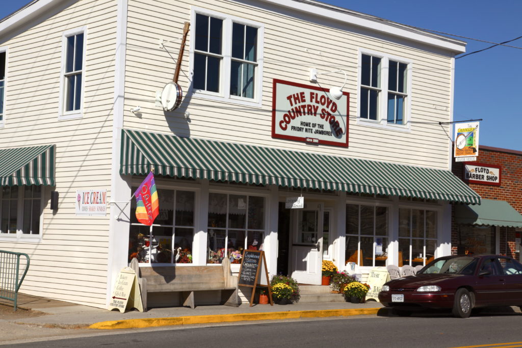 Floyd Country Store's green and white awning highlights the tan exterior of the two story building with windows along the front at street level.