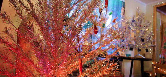 A bright pink aluminum tree glitters in Christmas lights.
