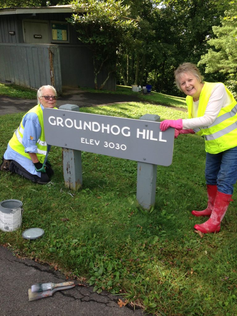 Two volunteers clean a sign at Rocky Knob along the Parkway.