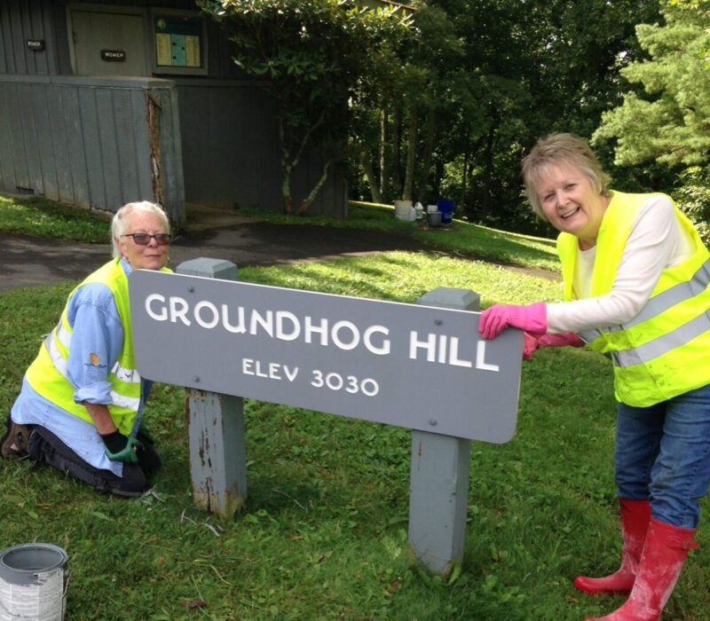 Two volunteers clean a sign at Rocky Knob along the Parkway.