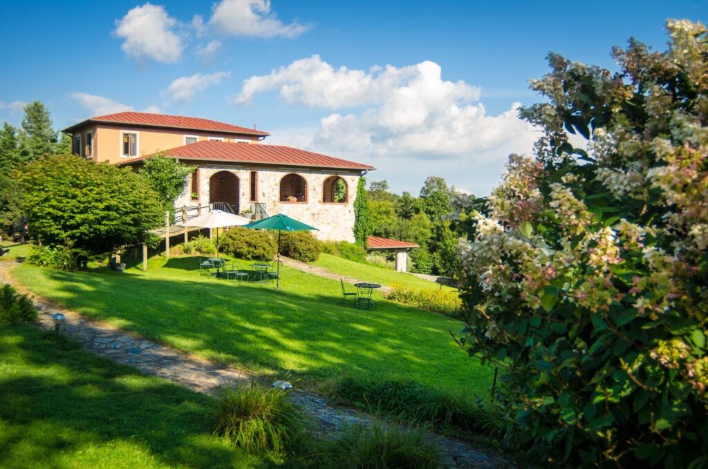 Villa Appalaccia Winery is a Tuscan-style building with a tile roof set on a sloping grassy lawn.