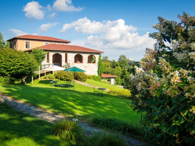 Villa Appalaccia Winery is a Tuscan-style building with a tile roof set on a sloping grassy lawn.