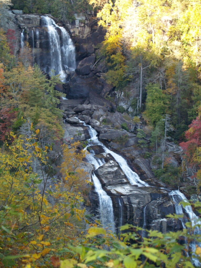 411-foot Whitewater Falls drops over the rocks into multiple streams surrounded by fall-colored leaves.