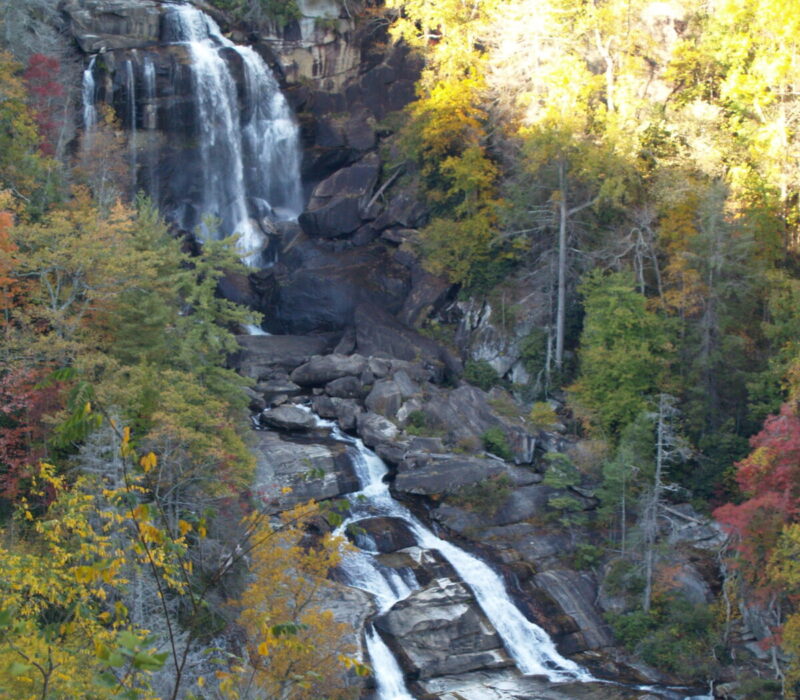 411-foot Whitewater Falls drops over the rocks into multiple streams surrounded by fall-colored leaves.