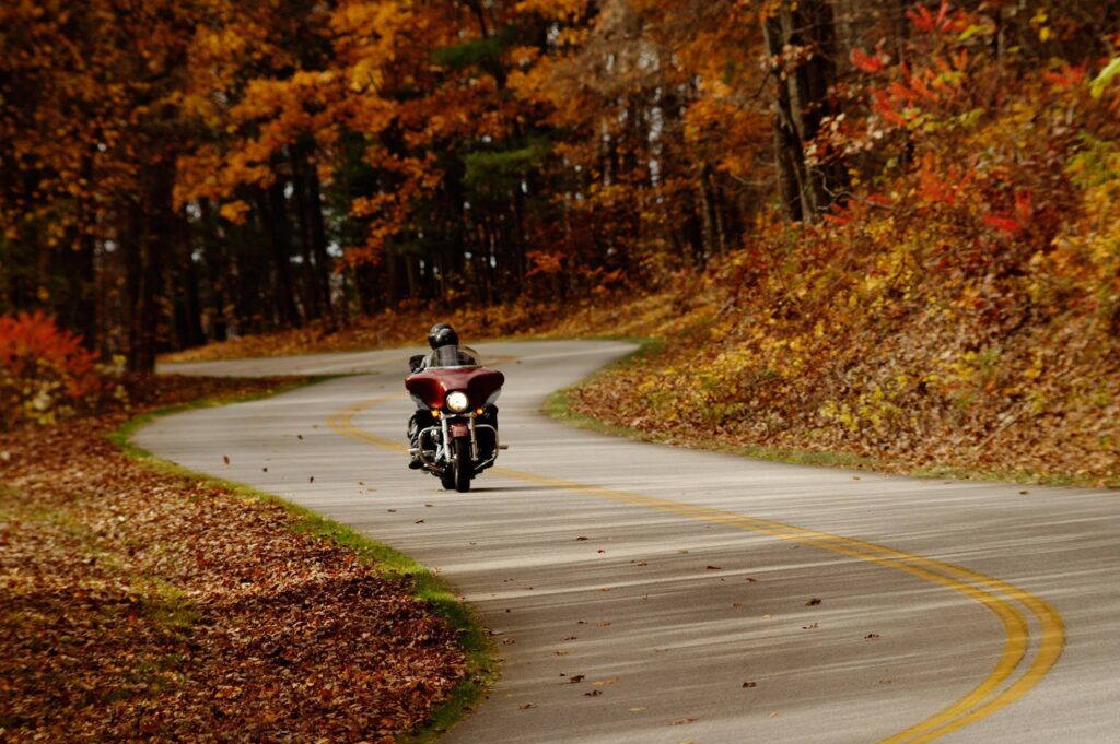 A motorcyclist travels a curvy road in Autumn