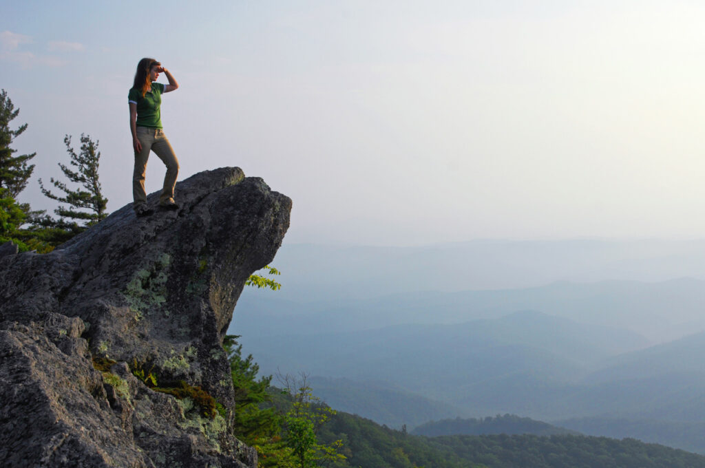 A visitor stands atop the rock overlooking the valley below at The Blowing Rock attraction.