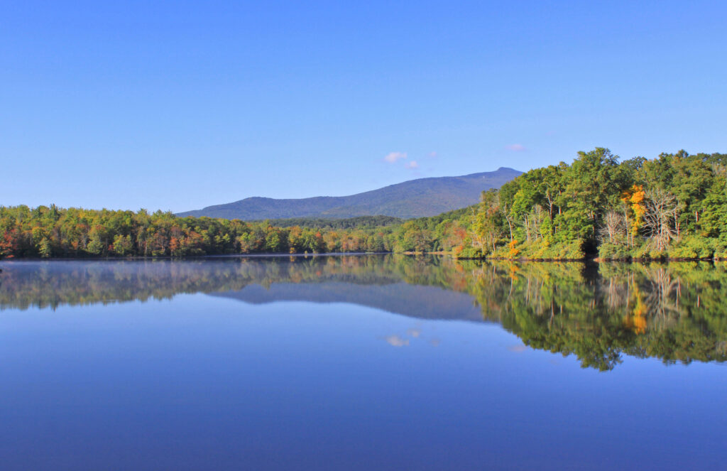 Fall colors are starting to show on the trees surrounding Price Lake with the mountains in the background on an almost-cloudless day.
