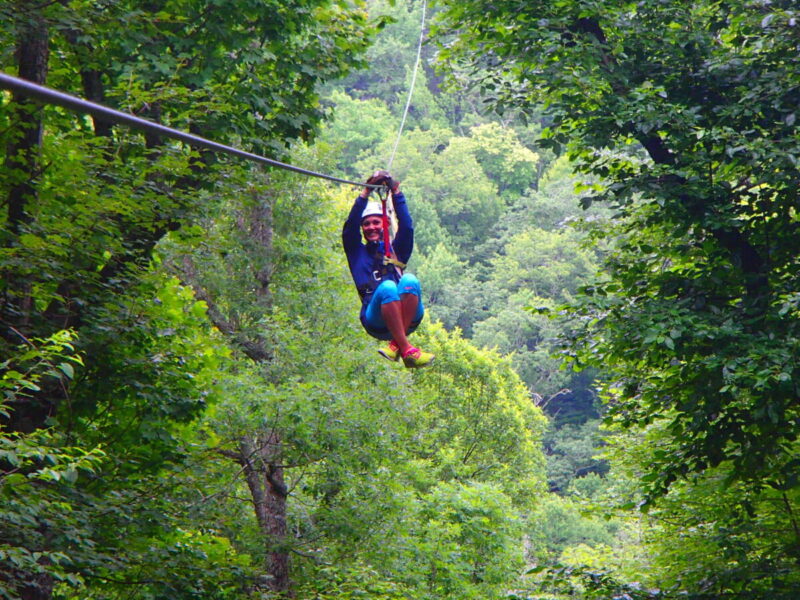An adventurer zips through the forest canopy at Sky Valley Zip Tours.