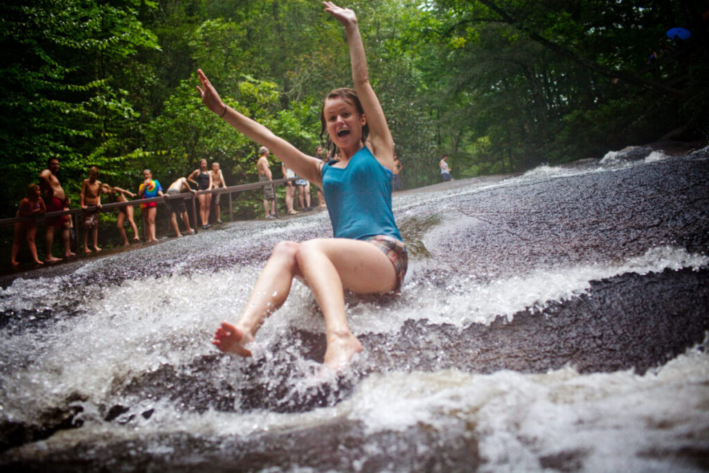 A girl slides down sliding rock.