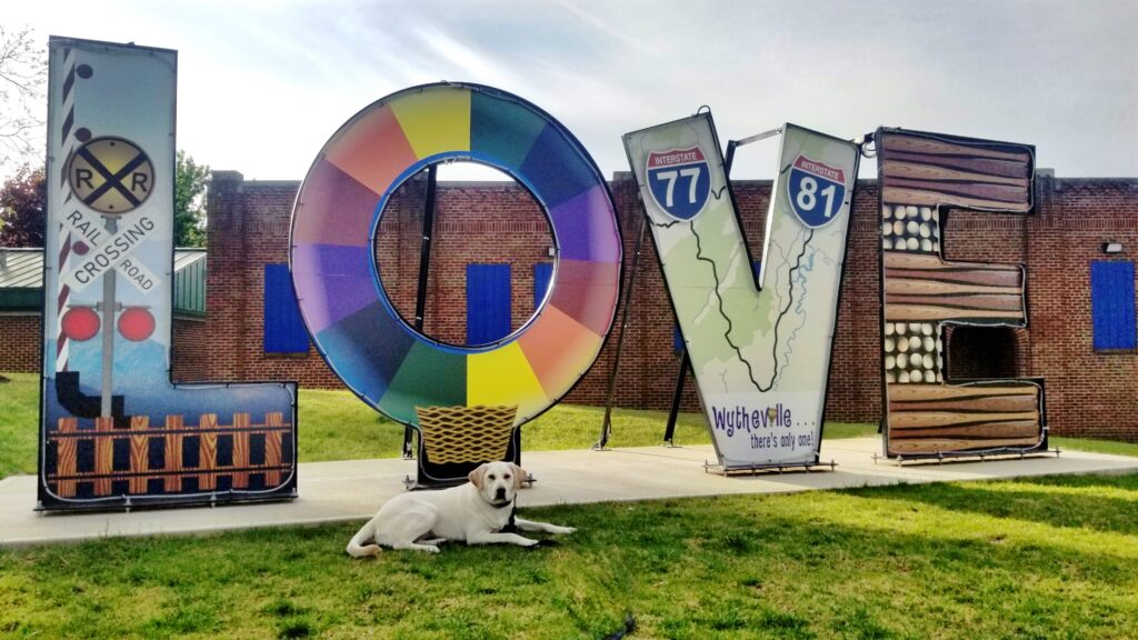 A golden retriever lies in front of the LOVE sign in downtown Wytheville, VA.