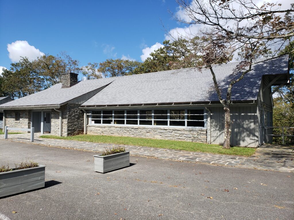 The Bluffs Restaurant at Doughton Park is a typical NPS facility with lots of stonework, a shingled roof and a cobblestone sidewalk set behind a wide paved area.