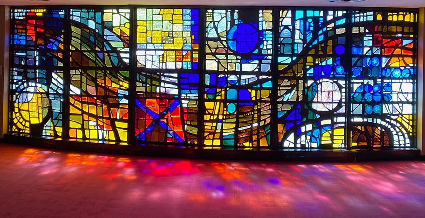 The light shines through the large stained glass wall at the Virginia Museum of the Civil War, displaying shades of red, blue and yellow on the maroon carpet.