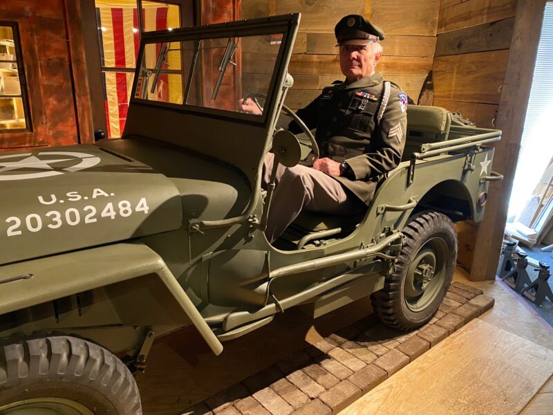 A uniformed veteran sits in a 1943 Willys military Jeep.