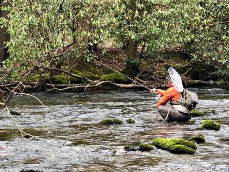 A fly fisherman casts his line in a rocky river.