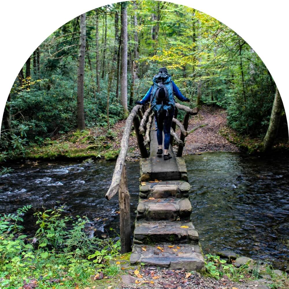 a hiker crosses a wooden bridge in the great smoky mountains