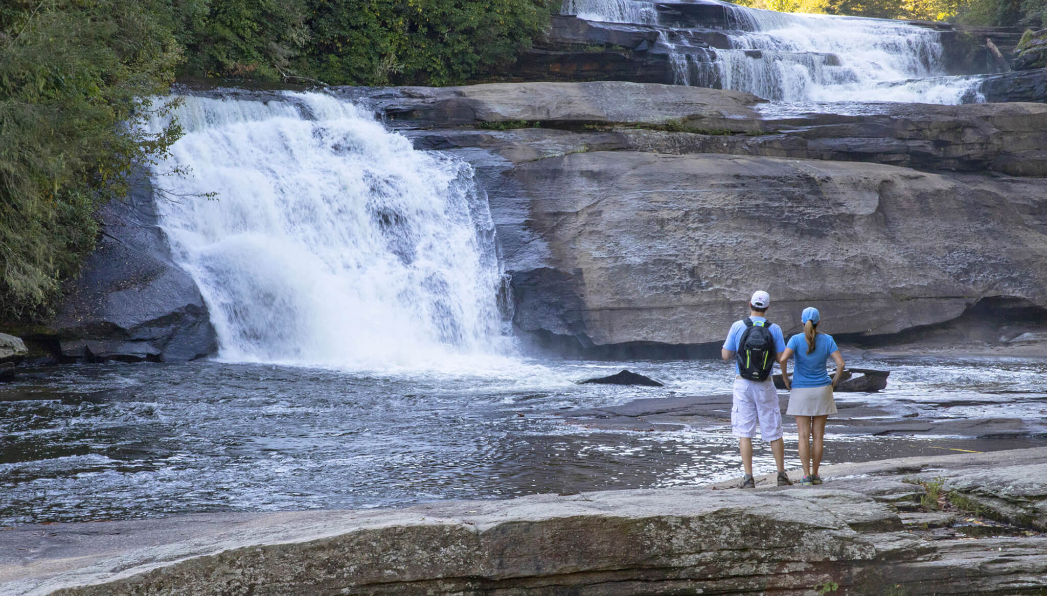 a couple admires a waterfall found along the blue ridge parkway