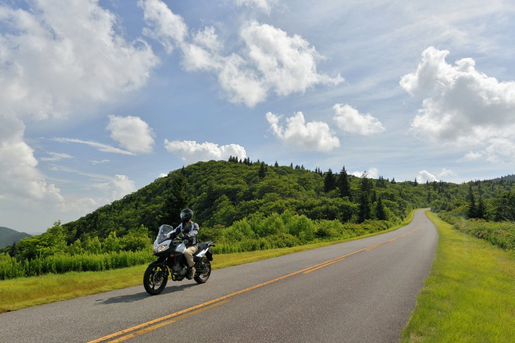 a motorcycle drives on a paved road along the blue ridge parkway